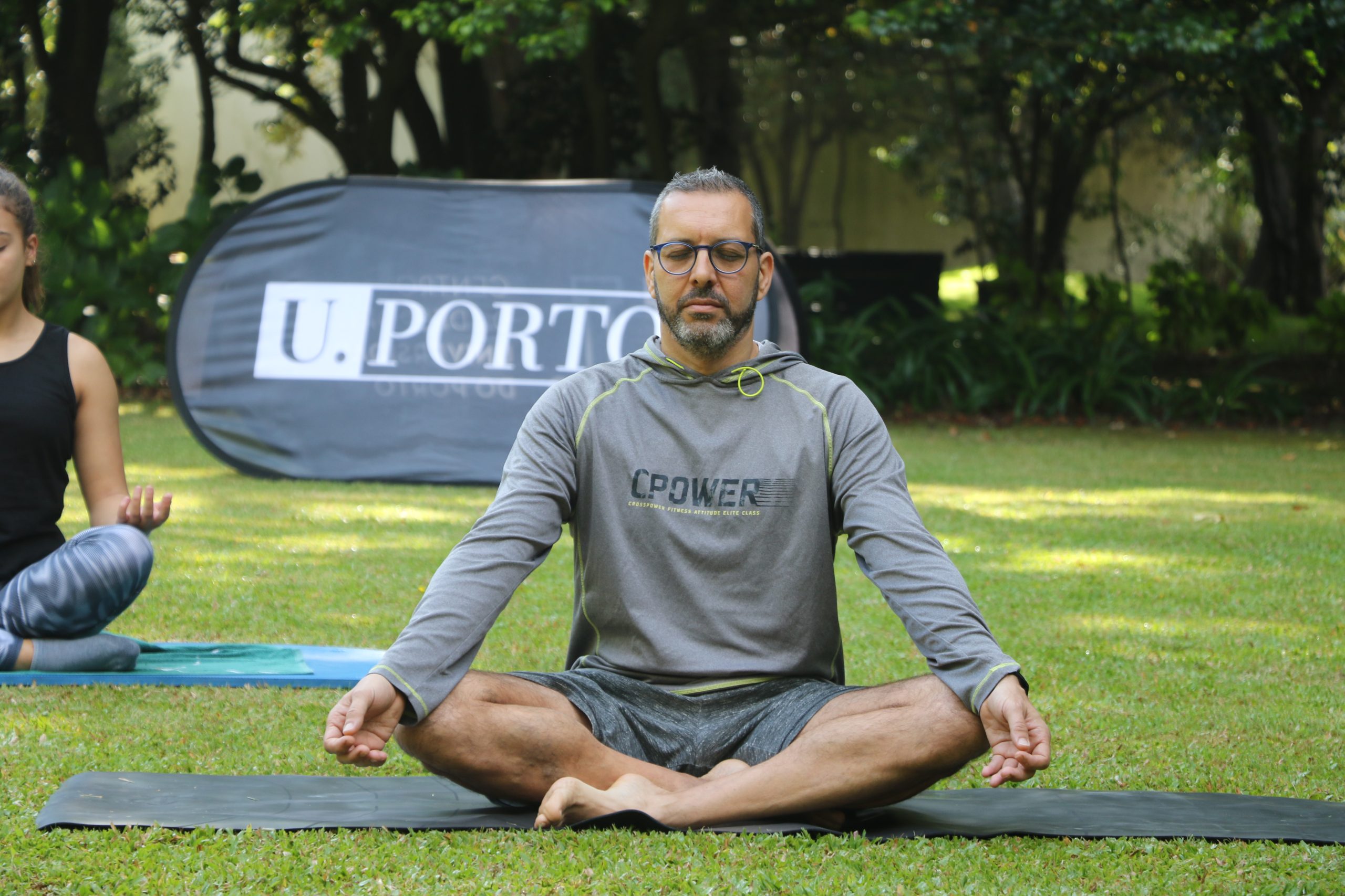 Homem de pernas cruzadas na relva enquanto faz yoga.