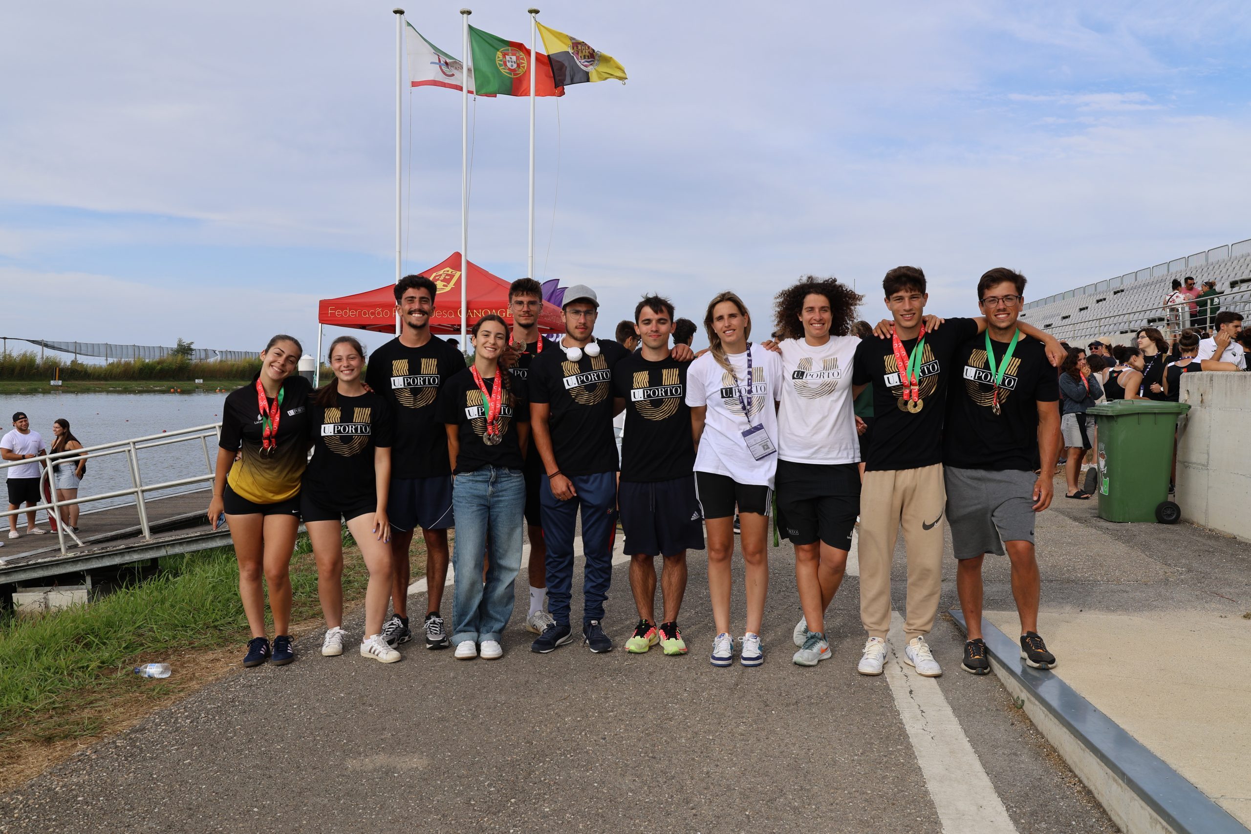 9 estudantes-atletas em fila. 3 mulheres e 6 homens acompanhados por 2 oficiais, 1 treinadora e 1 oficial.